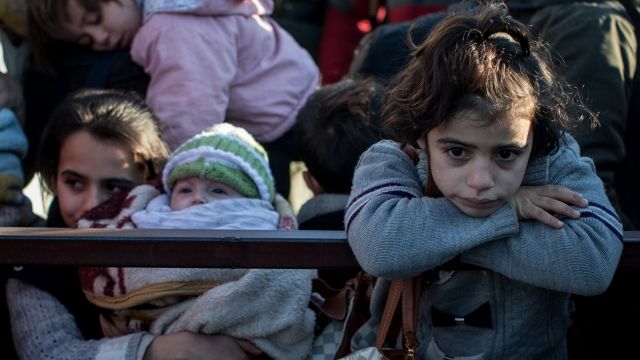 Migrants children wait at a station