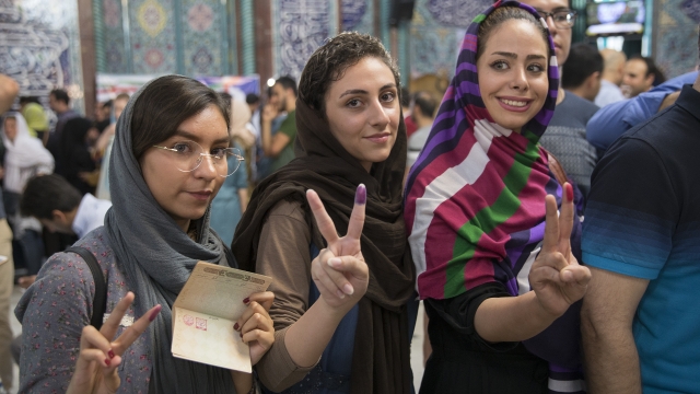 Iranians show their fingers dipped in ink, proving that they voted.