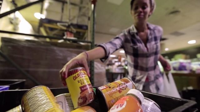 A woman picks up a can at a food pantry