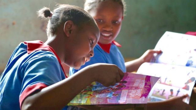 Girls looking at a magazine about menstrual health