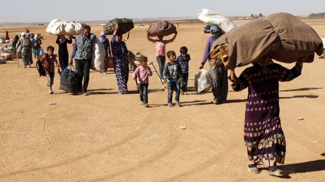 Syrian Kurdish Refugees walk their belongings into Turkey