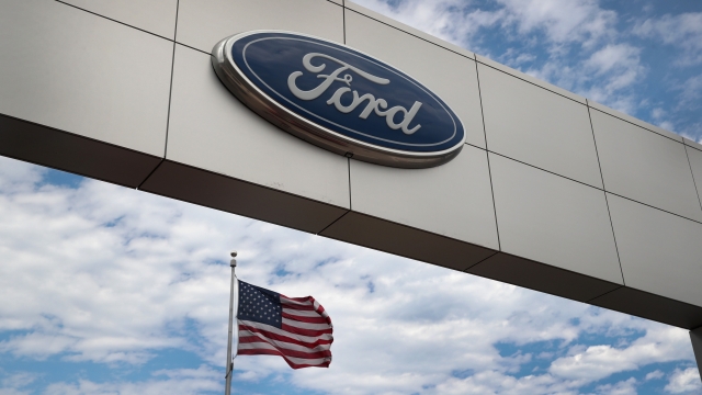 A sign sits in front of a Ford dealership.