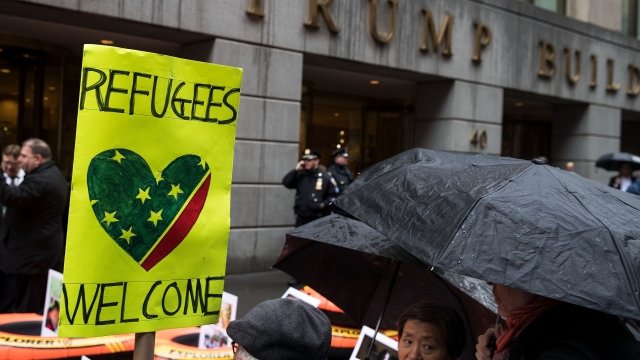 refugees welcome sign and protesters in front of trump building