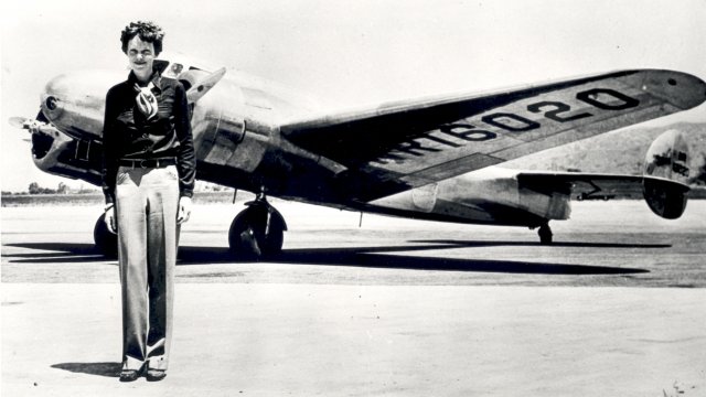 Amelia Earhart standing in front of her plane