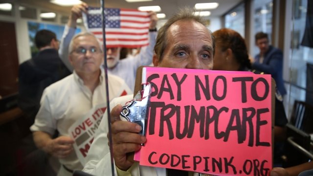 Protesters of the proposed health care bill hold signs.