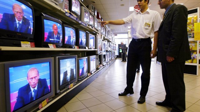 Men watch a news conference of Russian president Vladimir Putin on TVs in a store June 24, 2002 in Moscow.