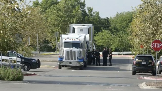 Police investigate a tractor-trailer where dozens of people were found crowded inside.