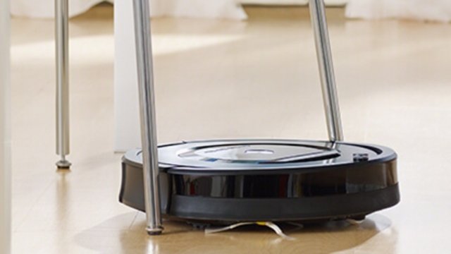 A Roomba cleans under a chair