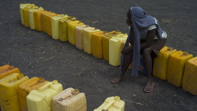 A person from South Sudan sits on water jugs
