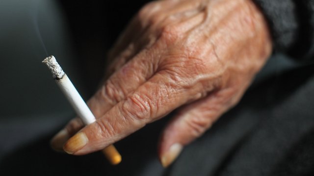 A close-up of an individual's hand while they smoke a cigarette