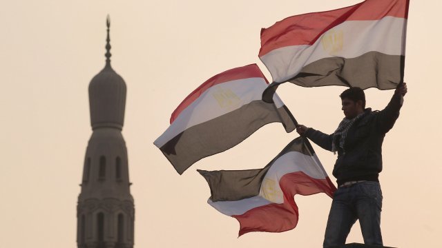 A youth waves Egyptian flags from a lamp post in Tahrir Square on February 1, 2011 in Cairo, Egypt.