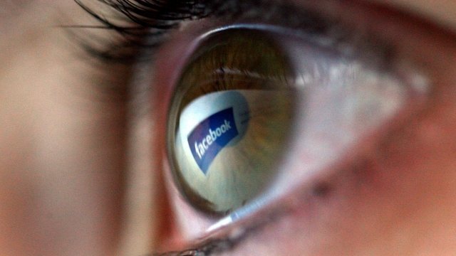 The Facebook logo is reflected in the eye of a girl.