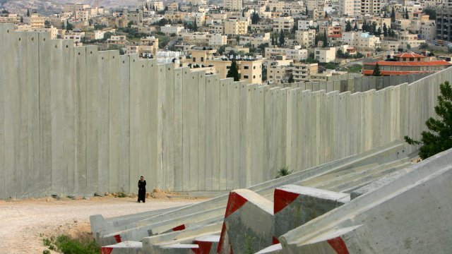 Palestinian woman walks along the border wall on the West Bank.
