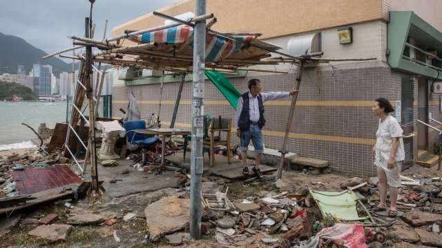 Hong Kong residents standing in damage from Typhoon Hato