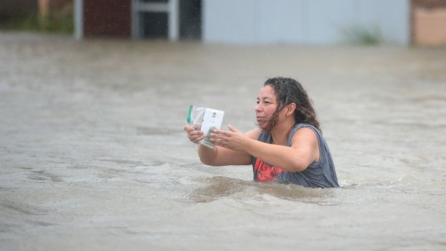Woman carries smartphone through flood.