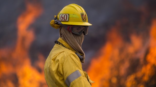 Flames rise behind California firefighter.