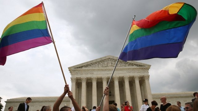 People wave LGBT flags at the Supreme Court