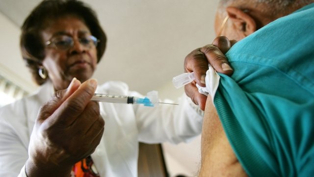 A woman administers a flu shot to a patient