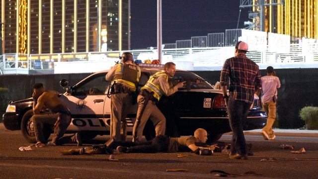 Officers and bystanders hide behind a police car in Las Vegas