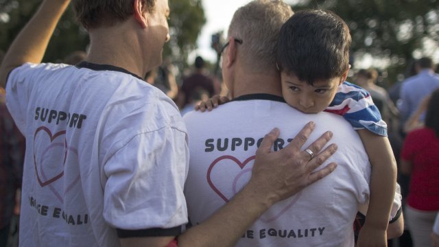 Mark Beckfold and Steve Ledoux, who are married, hold their foster son at a celebration of the Supreme Court ruling.