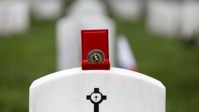 A Purple Heart challenge coin is seen atop a headstone at Arlington National Cemetery