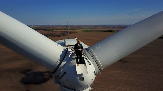 Reporter Zach Toombs climbs onto the head of a wind turbine over rural Iowa