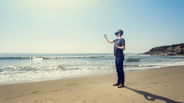 A student wears a virtual reality headset on the beach