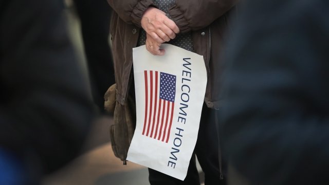 Refugee supporter holding welcome home sign with U.S. flag