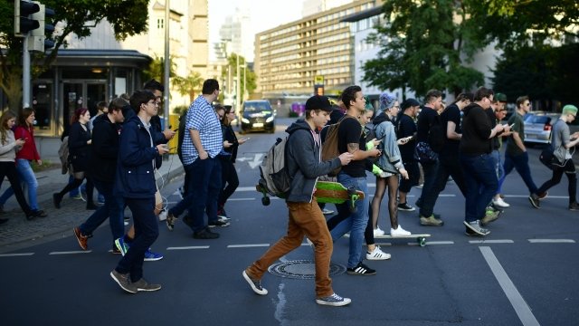 Young people walk through the city center of Hanover while holding their smartphones.