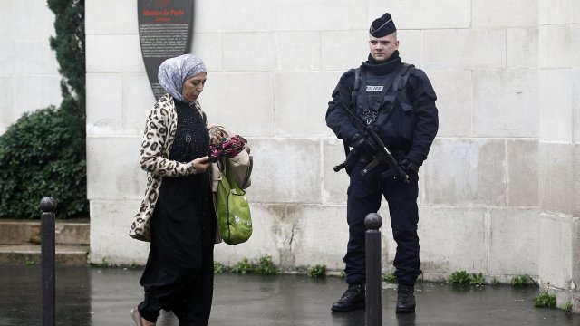A Muslim woman walks past a police officer in Paris.