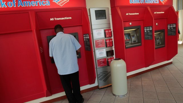 A man operates an automated teller machine at a Bank of America branch bank in midtown Manhattan.