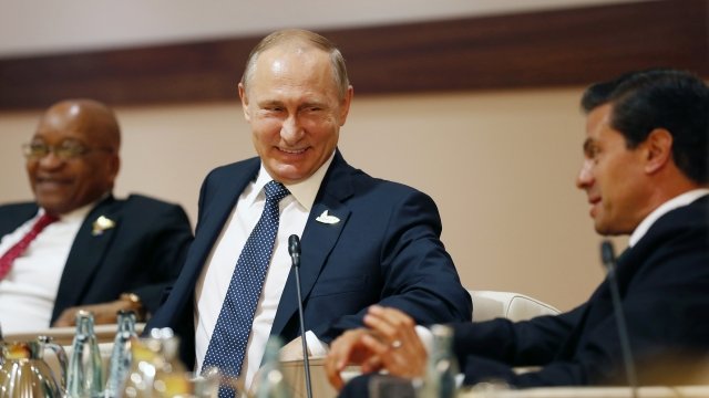 Vladimir Putin smiles at a meeting