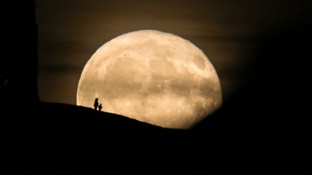 A pair of silhouetted figures stand in front of the moon on November 4, 2017 in Somerset, England.