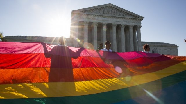 Supporters of same-sex marriage unfurl a large rainbow pride flag near the Supreme Court in Washington, D.C.