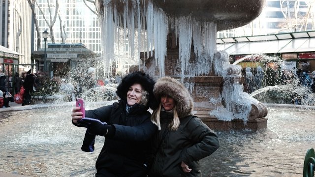 Two women take a selfie photo in front of a frozen fountain in Bryant Park on a frigid day in Manhattan.