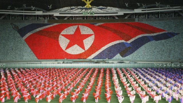 North Koreans perform showing the North Korean national flag.