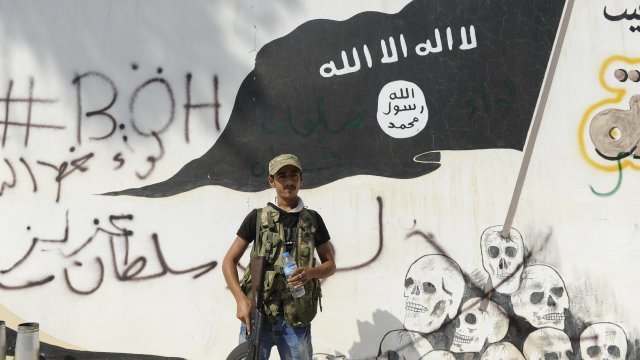 A member of the Turkish-backed Free Syrian Army stands guard in front of an ISIS flag