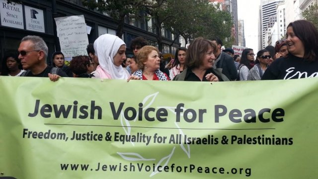 Protesters are holding a Jewish Voice for Peace banner