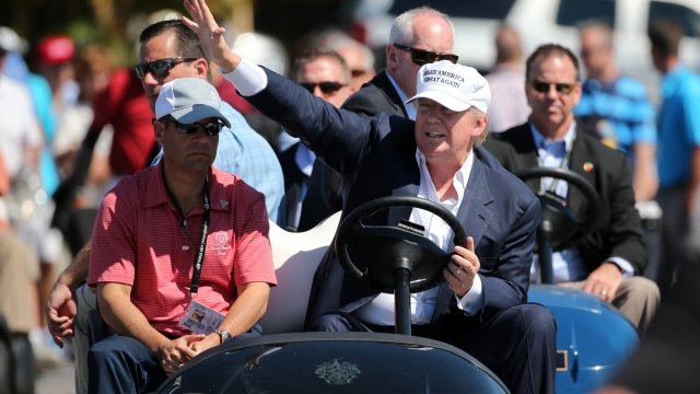 Trump rides golf cart.