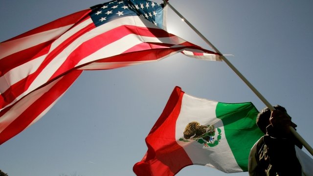 A protester holds an American flag and a Mexican flag