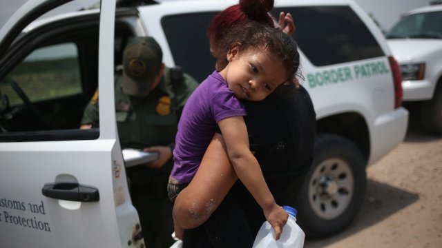 A mother and child, 3, from El Salvador await transport to a processing center for undocumented immigrants.