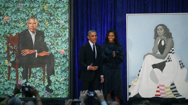 Former U.S. President Barack Obama and former first lady Michelle Obama stand next to their newly unveiled portraits.