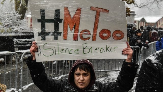 People carry signs addressing sexual harassment at a #MeToo rally