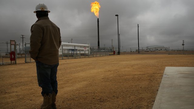 A worker watches a natural gas flare burn off