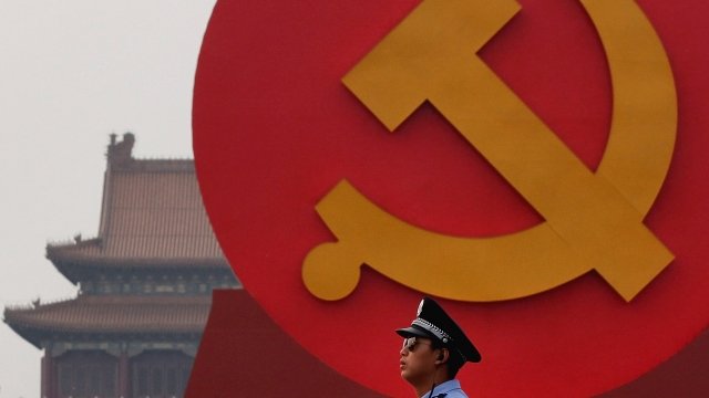A policeman patrols in front of a communist symbol in China