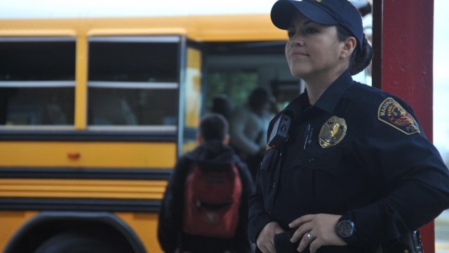 School resource officer stands near buses.