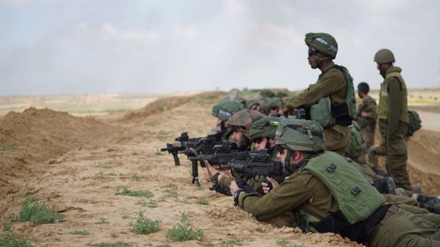 Israeli soldiers crouch holding guns