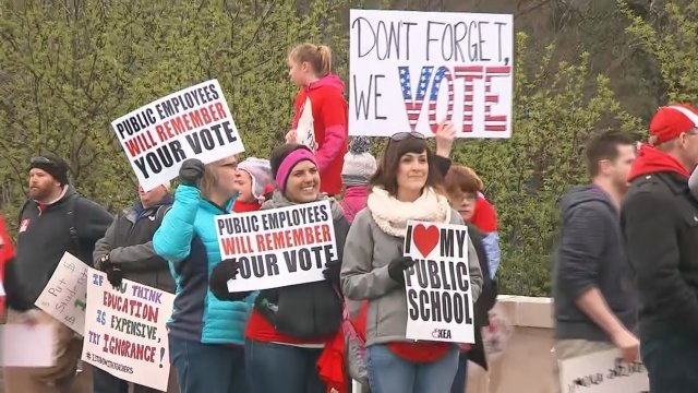 Kentucky teachers march in protest holding signs.