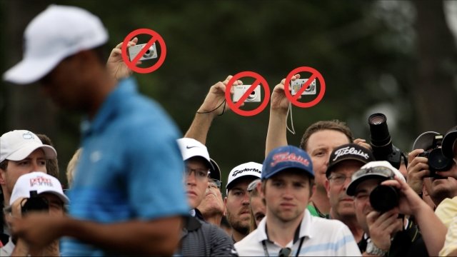Cameras held by spectators at a golf event are crossed out with red marks.