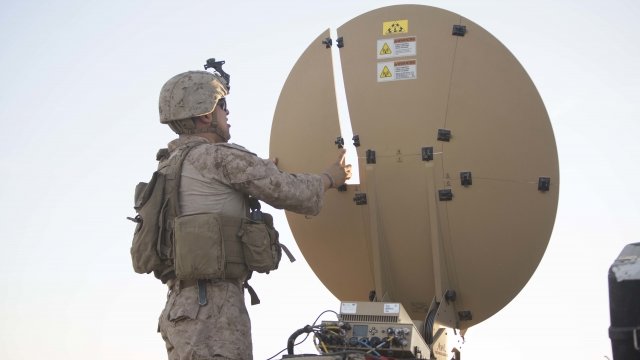 A soldier standing next to a satellite dish in Iraq